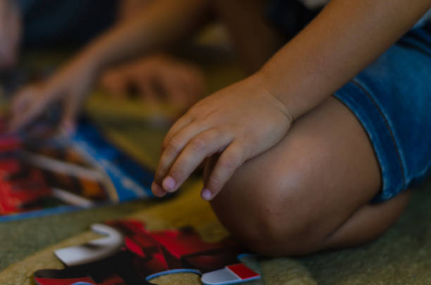 istock A boy of mixed race playing puzzles while sitting on the floor inside the room. 1269796945