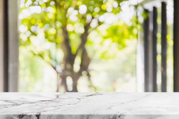 istock Empty white marble stone table top and blurred living room in home interior with green tree outside window background. - can used for display or montage your products. 1269797668