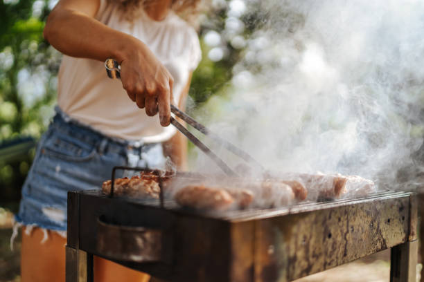 Smiling woman preparing barbecue at backyard