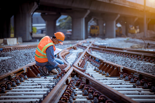 Portrait engineer under inspection and checking construction process railway switch and checking work on railroad station .Engineer wearing safety uniform and safety helmet in work.