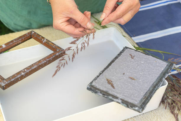 Woman holding frame for making paper sheets from waste paper pulp. Selective focus. Decorative and applied art. Recycling concept, ecology.