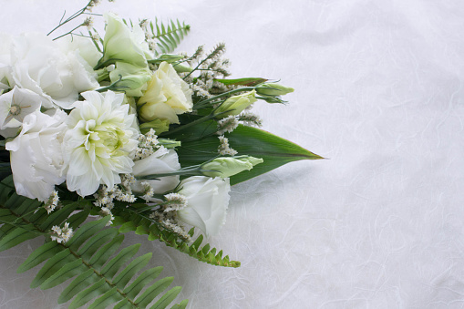 Flower arrangement of several kinds of white flowers and leaves.