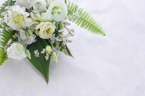 Flower arrangement of several kinds of white flowers and leaves.