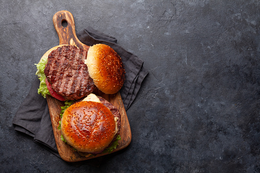 Colorful and tasty burger on a homemade wooden cutting board and dark background