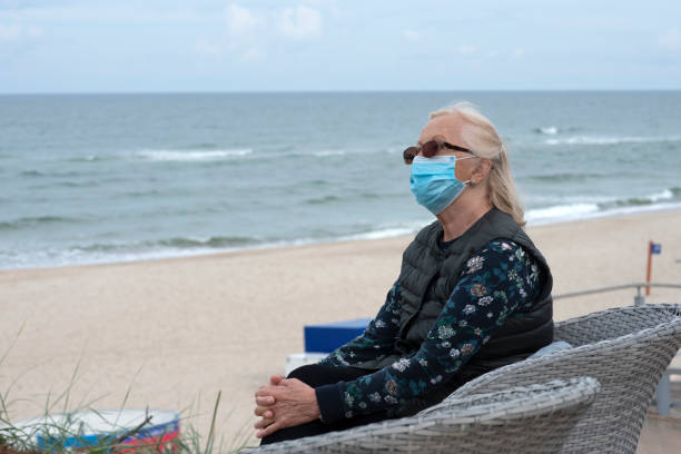 istock Senior woman with protective mask on the beach. 1269806584