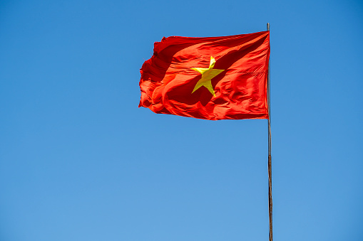 Red Vietnam flag against the blue sky, close up