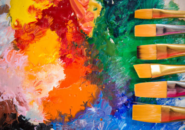 istock Acrylic or water color paint and brushes on wooden palette with copy space. Difference size of brushes over color paint background. Artist creative education concept banner 1269809452