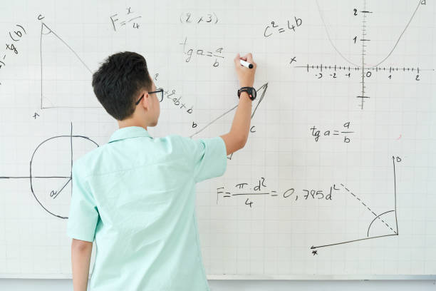Schoolboy writing geometry equation Schoolboy in glass writing geometry equation on whiteboard, view from the back algebra stock pictures, royalty-free photos & images