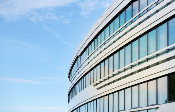 façade d’un immeuble de bureaux incurvé et ciel bleu - glass architecture prosperity business photos et images de collection