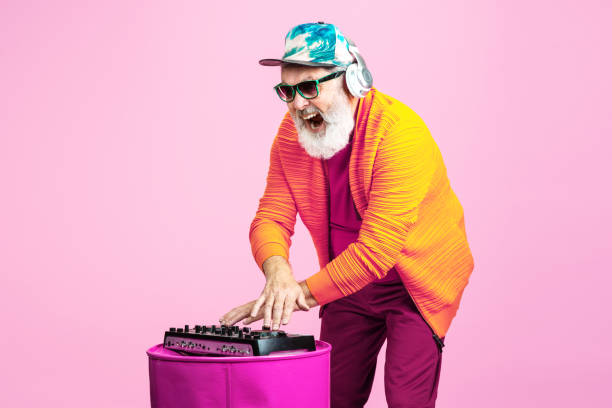 Senior hipster man wearing eyeglasses posing on pink background. Tech and joyful elderly lifestyle concept