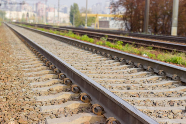 Modern railroad track with concrete sleepers and crushed stone track ballast close-up at selective focus