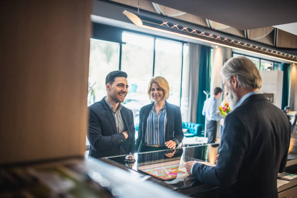 istock Bearded Hotel Receptionist Checking In Guests at Front Desk 1269813008
