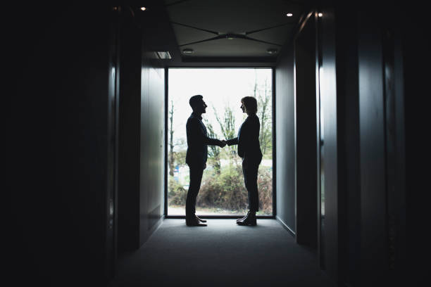 istock Business Associates Shaking Hands in Back Lit Hotel Corridor 1269813059
