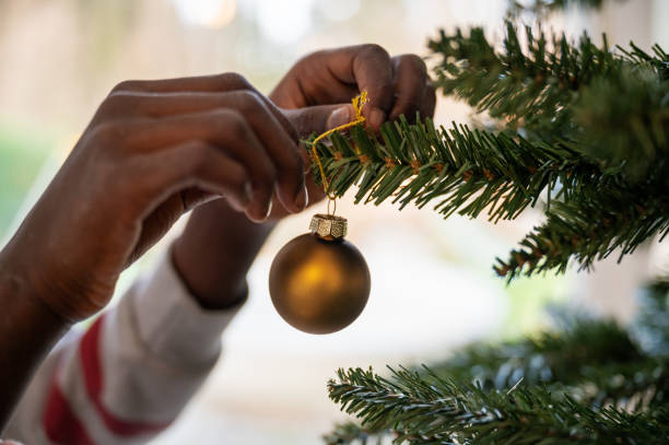 istock Colored child hanging golden holiday bauble on christmas tree 1269813187
