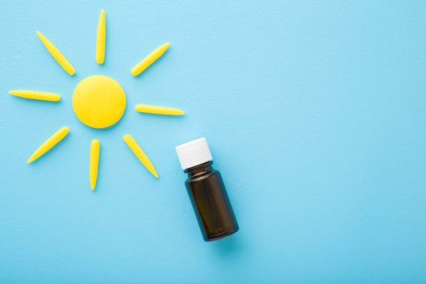 Brown glass bottle of d vitamin and yellow sun shape on light blue table background. Pastel color. Daily receiving vitamins. Closeup. Top down view. Brown glass bottle of d vitamin and yellow sun shape on light blue table background. Pastel color. Daily receiving vitamins. Closeup. Top down view. glass medicine blue bottle stock pictures, royalty-free photos & images