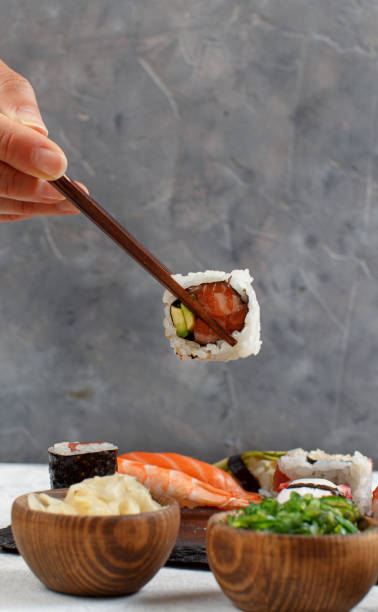 istock Close up of hand taking roll with chopsticks from a plate 1269816999