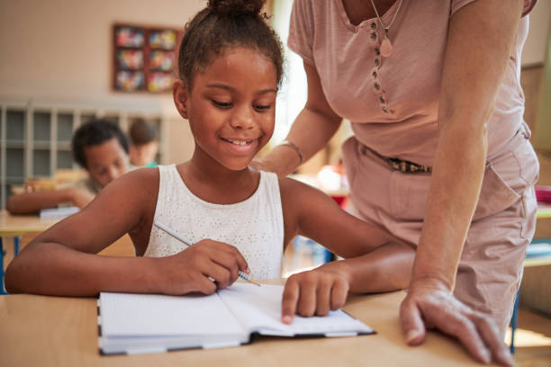 istock Elementary teacher praise diligent diverse school girl after she doing amazing homework 1269827083