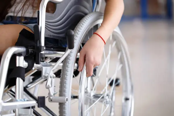 A young girl in a wheelchair is standing in the corridor of the hospital