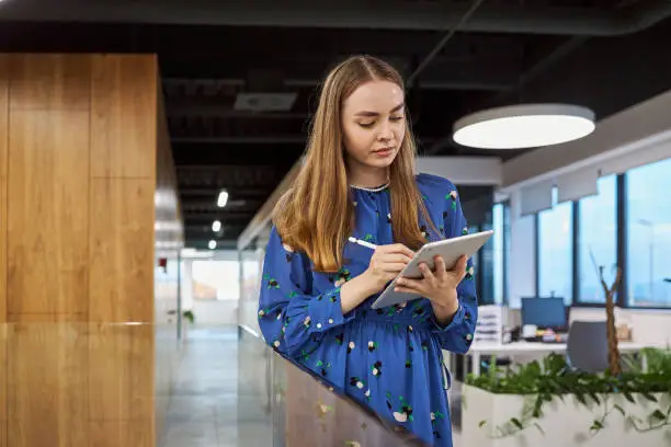 Modern young businesswoman holding an tablet computerd with graph documents and she analyzing them so she can present result later in a board meeting