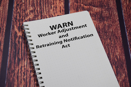 Libro sobre WARN - Ley de Notificación de Ajuste de Trabajadores & Reentrenamiento aislada en la mesa de madera. photo