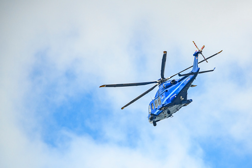 Blue and white helicopter in flight isolated against white background