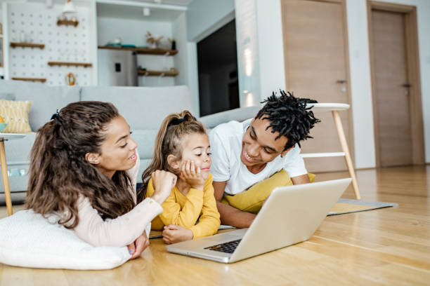 istock Young parents playing with child and using laptop at home 1269833261