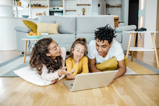 istock Young parents playing with child and using laptop at home 1269833267