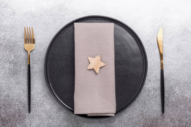 istock Christmas table setting with black ceramic plate, napkin, cutlery on stone background. Top view. Copy space 1269836784