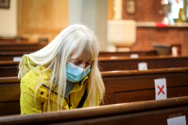 mujer mayor rezando en la iglesia usando máscara protectora para la cara - senior women caucasian one person religion fotografías e imágenes de stock
