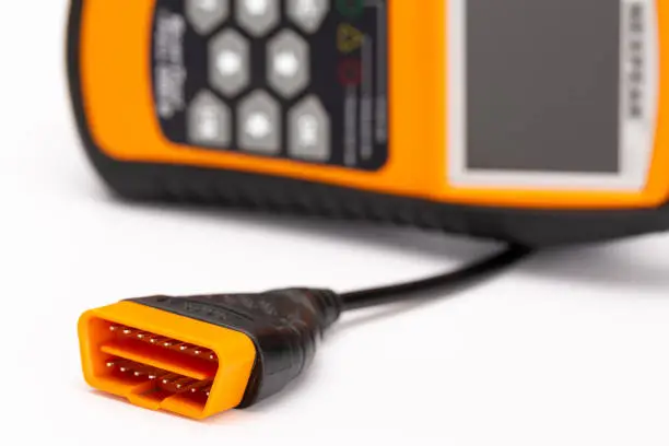 Close up of OBD 2 Plug with orange OBD-2 Car diagnostic tool in the background, on white background