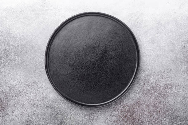 Empty black ceramic plate on stone background Copy space Top view stock photo