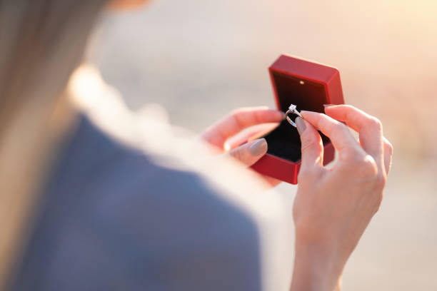 giovane donna che tiene in mano un anello di diamanti al tramonto - jewelry ring luxury wedding foto e immagini stock