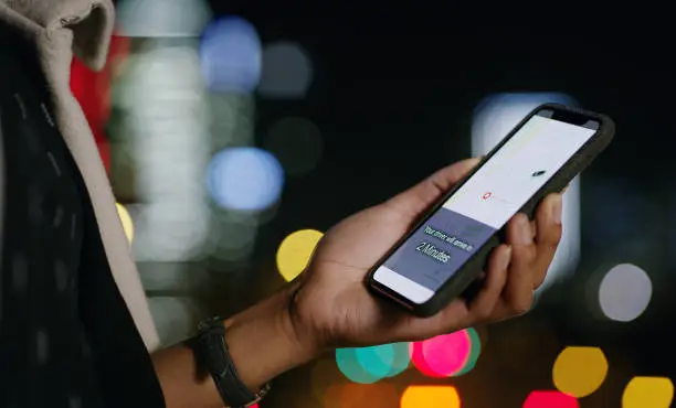 Cropped shot of a businesswoman using a smartphone to order a cab in the city at night