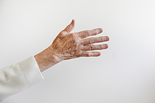 Cropped shot of elderly woman's hand over isolated white background. Wrinkled palm of unrecognizable senior lady. Close up, copy space for text.