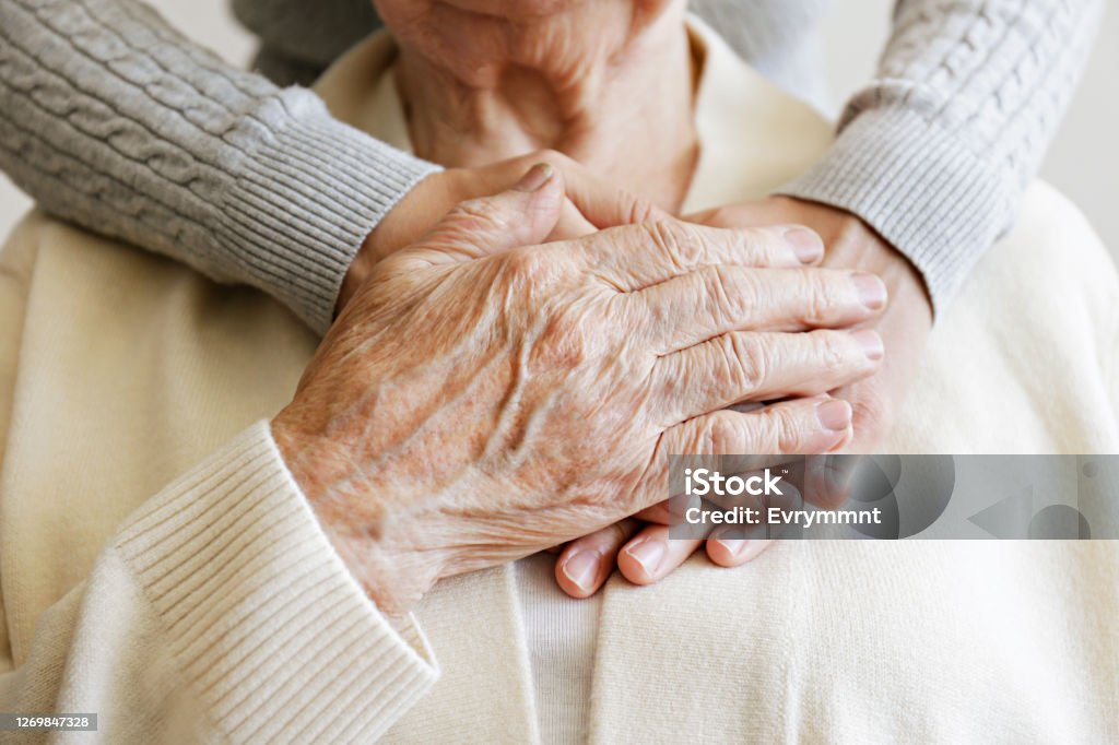 Cropped shot of elderly female's hands. Mature female in elderly care facility gets help from hospital personnel nurse. Senior woman, aged wrinkled skin & hands of her care giver. Grand mother everyday life. Background, copy space, close up Senior Adult Stock Photo