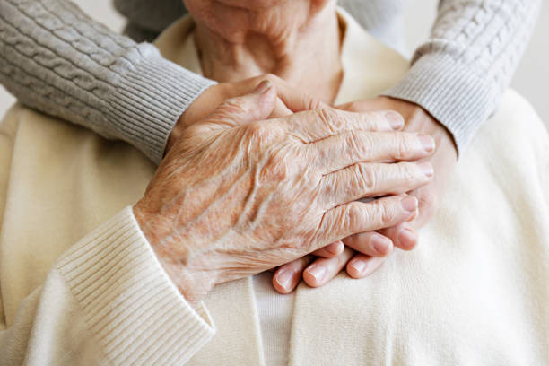 Cropped shot of elderly female's hands. Mature female in elderly care facility gets help from hospital personnel nurse. Senior woman, aged wrinkled skin & hands of her care giver. Grand mother everyday life. Background, copy space, close up touch sensitive stock pictures, royalty-free photos & images