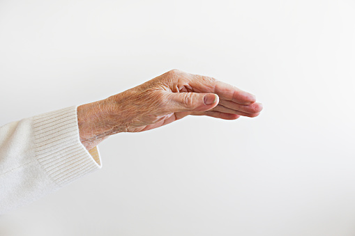 Cropped shot of elderly woman's hand over isolated white background. Wrinkled palm of unrecognizable senior lady. Close up, copy space for text.