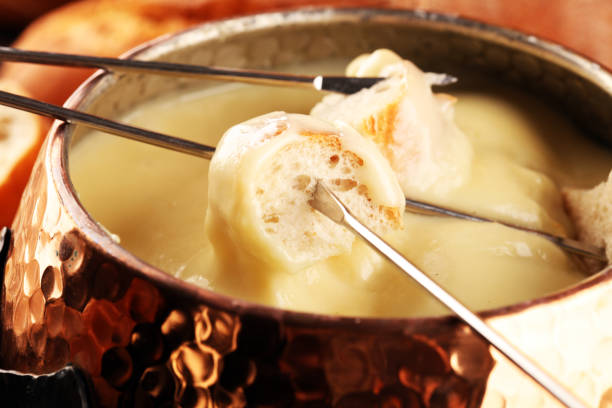 istock Gourmet Swiss fondue dinner on a winter evening with assorted cheeses on a board alongside a heated pot of cheese fondue with two forks dipping 1269847423
