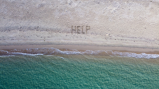 Help written on exotic sand beach with tropic blue sea.