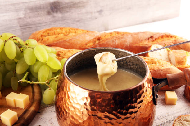 istock Gourmet Swiss fondue dinner on a winter evening with assorted cheeses on a board alongside a heated pot of cheese fondue with two forks dipping 1269847498