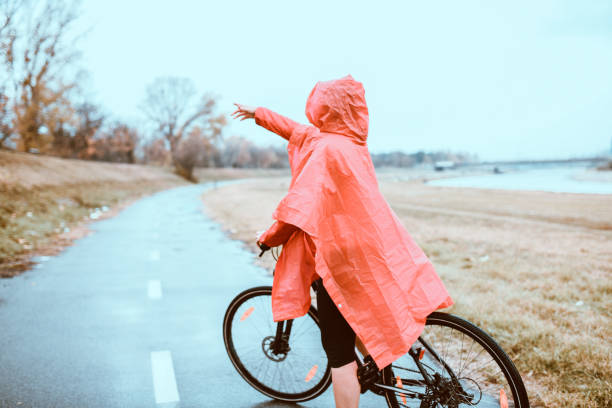 istock Female Cyclist Pointing To Her Next Destination During Rainy Park Ride 1269847532