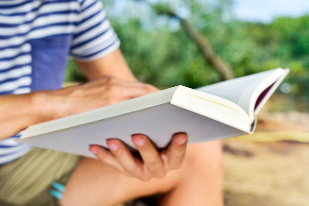 istock young man reading a book outdoors 1269850078