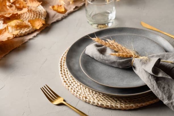 Autumn table setting with dry yellow oak leaves, fall decoration on grey. Thankisgiving day