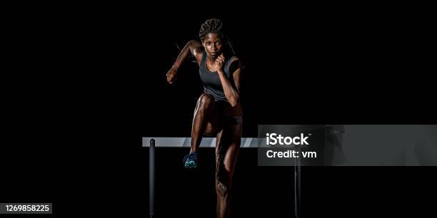 Africanamerican Woman Running Away From A Hurdle Stock Photo - Download Image Now - Athlete, Running, Females