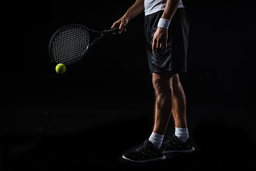 Caucasian tennis player tapping the ball with his racket.