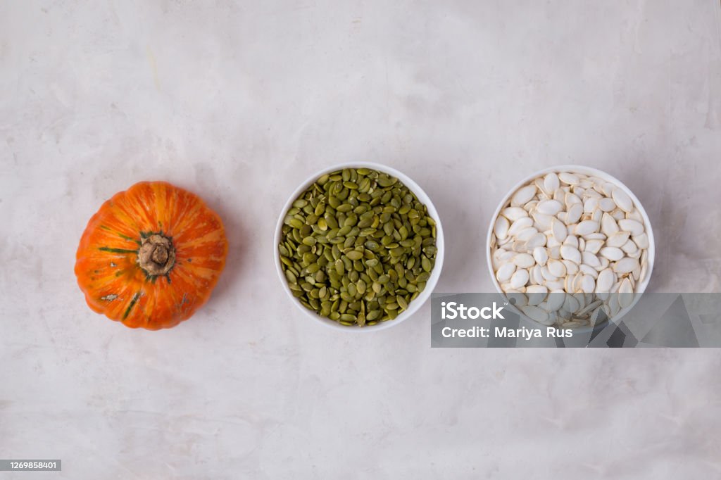 Pumpkin seeds are white and peeled green in white bowls. pumpkin.  Image contains space for text Pumpkin seeds are white and peeled green in white bowls. pumpkin. Top view Image contains space for text Bowl Stock Photo