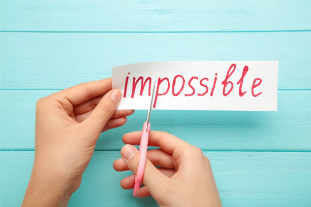istock Hand holding card with the text impossible, cutting the word im so it written possible. success and challenge concept. 1269859945
