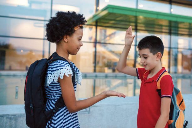 istock Two kids in a schoolyard greeting each other giving high five 1269861944