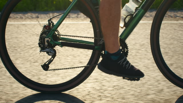 Close-up of the cyclist's legs. He is pedaling and the wheel is turning. Training on a bicycle. 4K