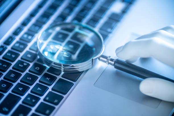 istock An artificial hand is holding a magnifying glass on the laptop while searching for information on the internet 1269864755